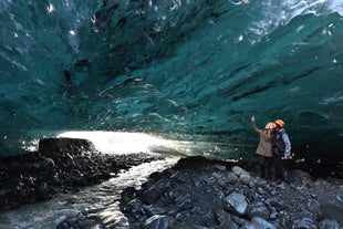 A stream creeps out of an Icelandic ice cave in winter.