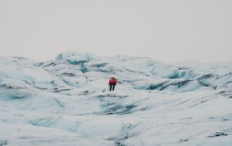 A person stands in the middle of the icy expanse of Solheimajokull glacier on a tour in Iceland.