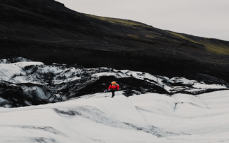 A person walks over the ice on Solheimajokull glacier.