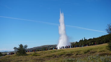 Strokkur geyser in Iceland erupts as tourists watch in amazement.