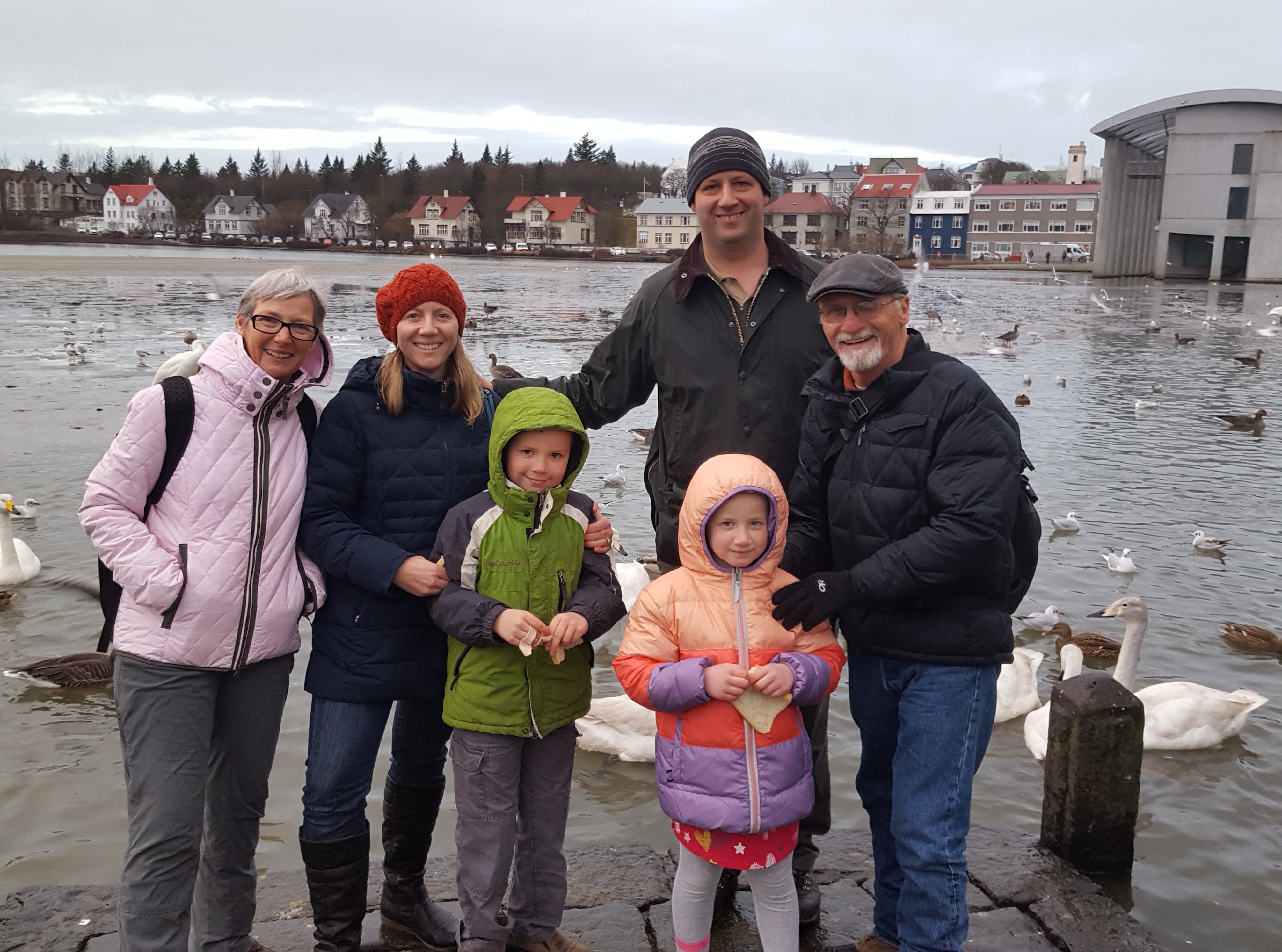 A family of travelers strike a pose by the Reykjavik Harbor.