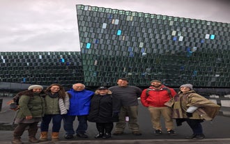 Grupa osób na pieszej wycieczce stojąca przed salą koncertową Harpa.