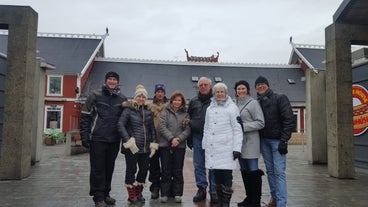 A group of people standing outside a building with a viking boat on it in Iceland.