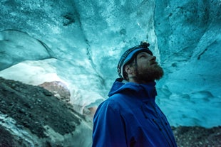 Een ijsspeleoloog bewondert de kleuren van de gletsjer van Skaftafell.