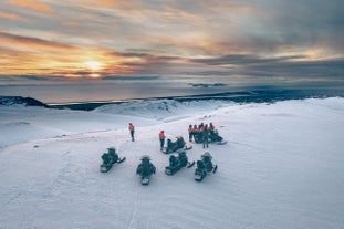 A group of people are seen from above on their snowmobiles on top of a glacier in Iceland.