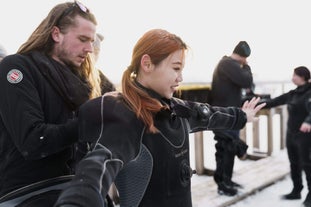 A woman gets zipped up in her drysuit by a man for a snorkeling tour in Silfra.
