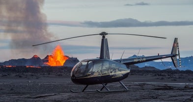 A helicopter is seen landed in front of an active eruption in Iceland.