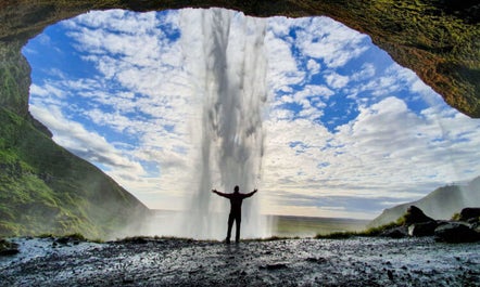 Eine Aufnahme aus dem Inneren einer Höhle, über die ein Wasserfall an der Südküste von Island fließt.