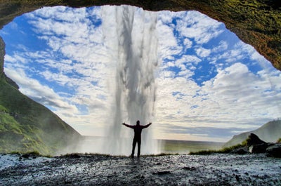 Eine Aufnahme aus dem Inneren einer Höhle, über die ein Wasserfall an der Südküste von Island fließt.