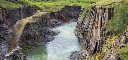 Acque che scorrono in un canyon fiancheggiato da colonne di roccia basaltica nell'est dell'Islanda
