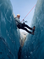 Homme descendant dans une crevasse du glacier Solheimajokull, équipé d'un casque et d'une corde de sécurité