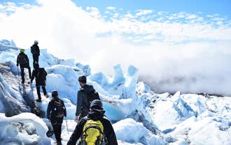 La gente camina sobre un glaciar en un día soleado.