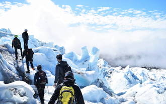 Persone che camminano in cima a un ghiacciaio durante una giornata di sole.