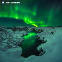 Nordlyset på Island lyser et sneklædt sceneri op.