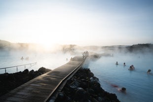 Vue panoramique du spa géothermique Blue Lagoon en Islande, où des personnes se baignent dans des eaux chaudes riches en minéraux.