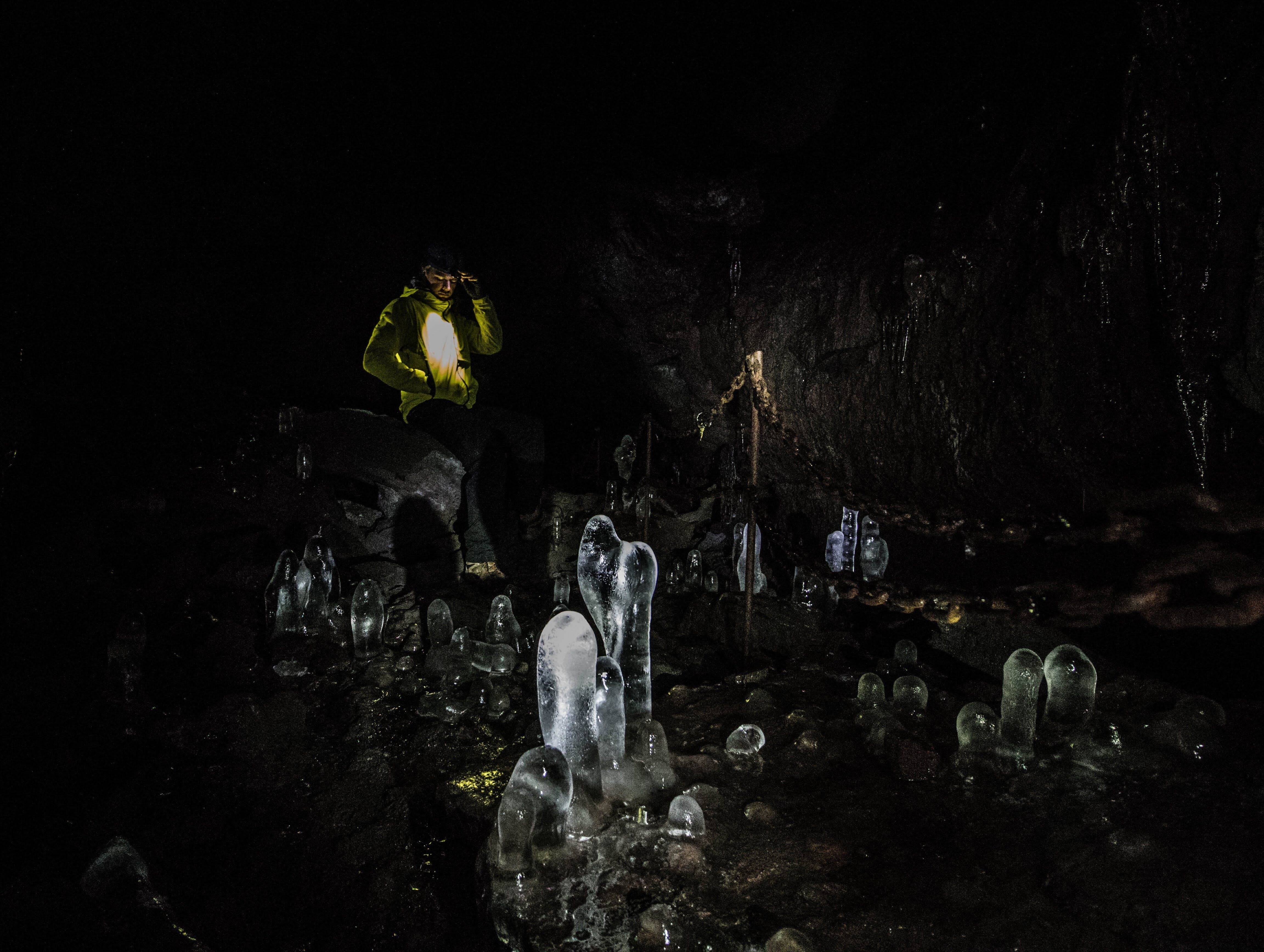A person stands near incredible frozen formations inside Leidarendi cave.