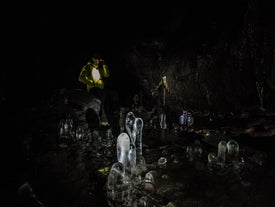 A person stands near incredible frozen formations inside Leidarendi cave.