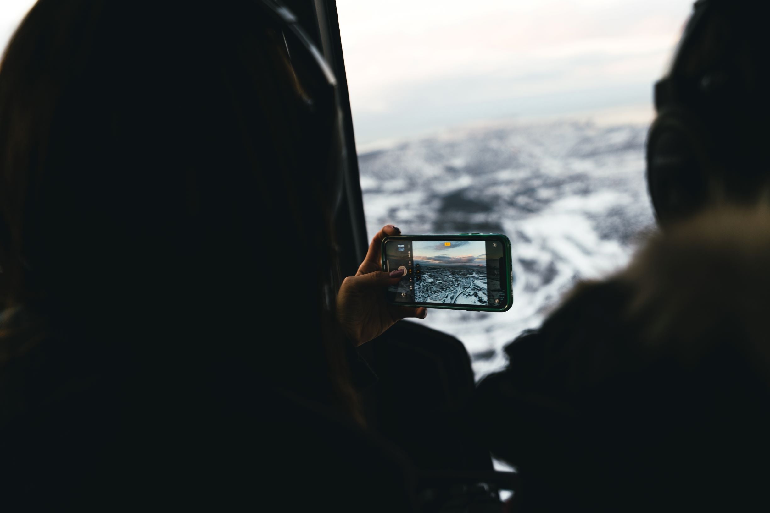 A woman capturing a picture of Reykjavik city scape on a helicopter ride