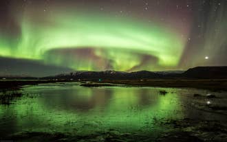 The northern lights show as green rings above a lake in North Iceland.