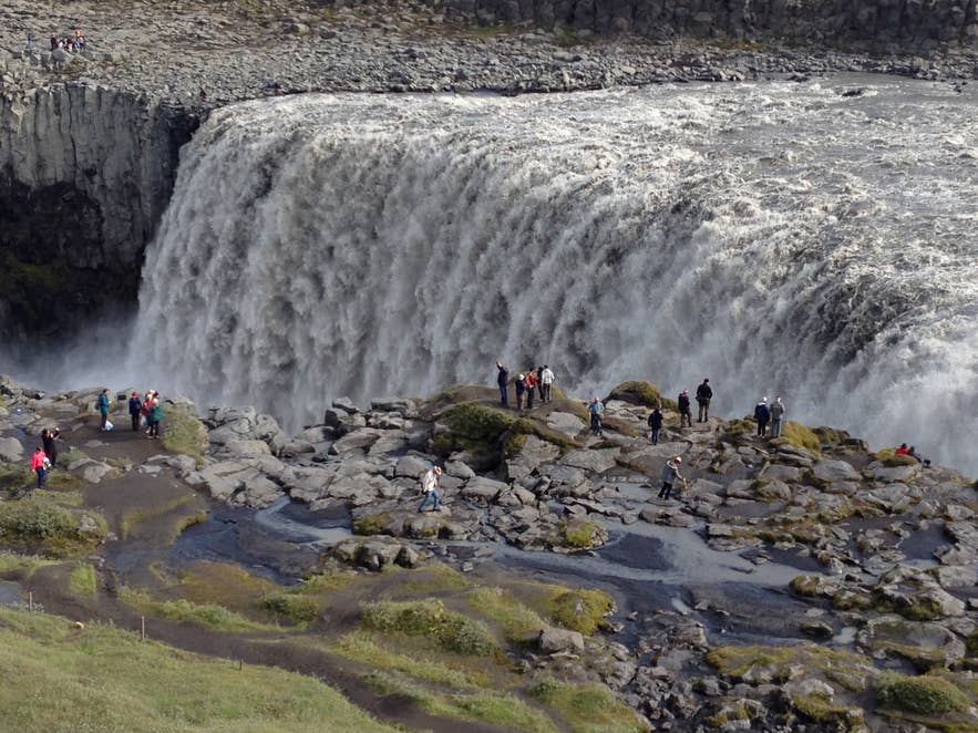 Tourists admiring Dettifoss Waterfall from the viewing platform.
