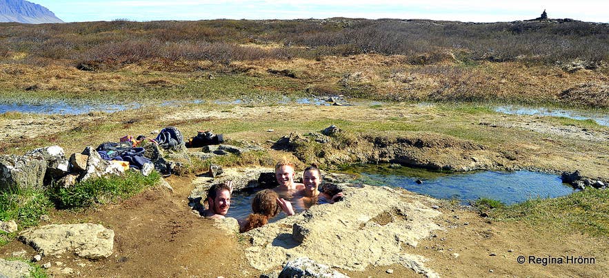 Bathers relaxing in the small Landbrotalaug Hot Spring behind its stone wall on the Snaefellsnes Peninsula.