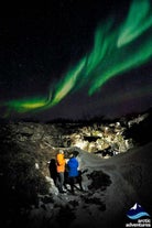 Two people watching the northern lights dance overhead.