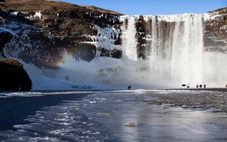 Skogafoss waterfall tumbles from a tall cliff in Iceland.