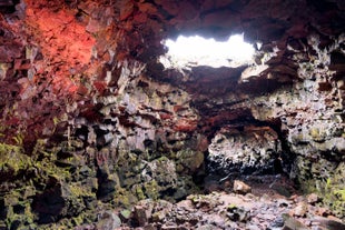 Inside Raufarholshellir Lava Tunnel which has a red glow on the walls.