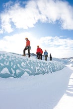 Group of people walking along a ridge of ice on Solheimajokull glacier.