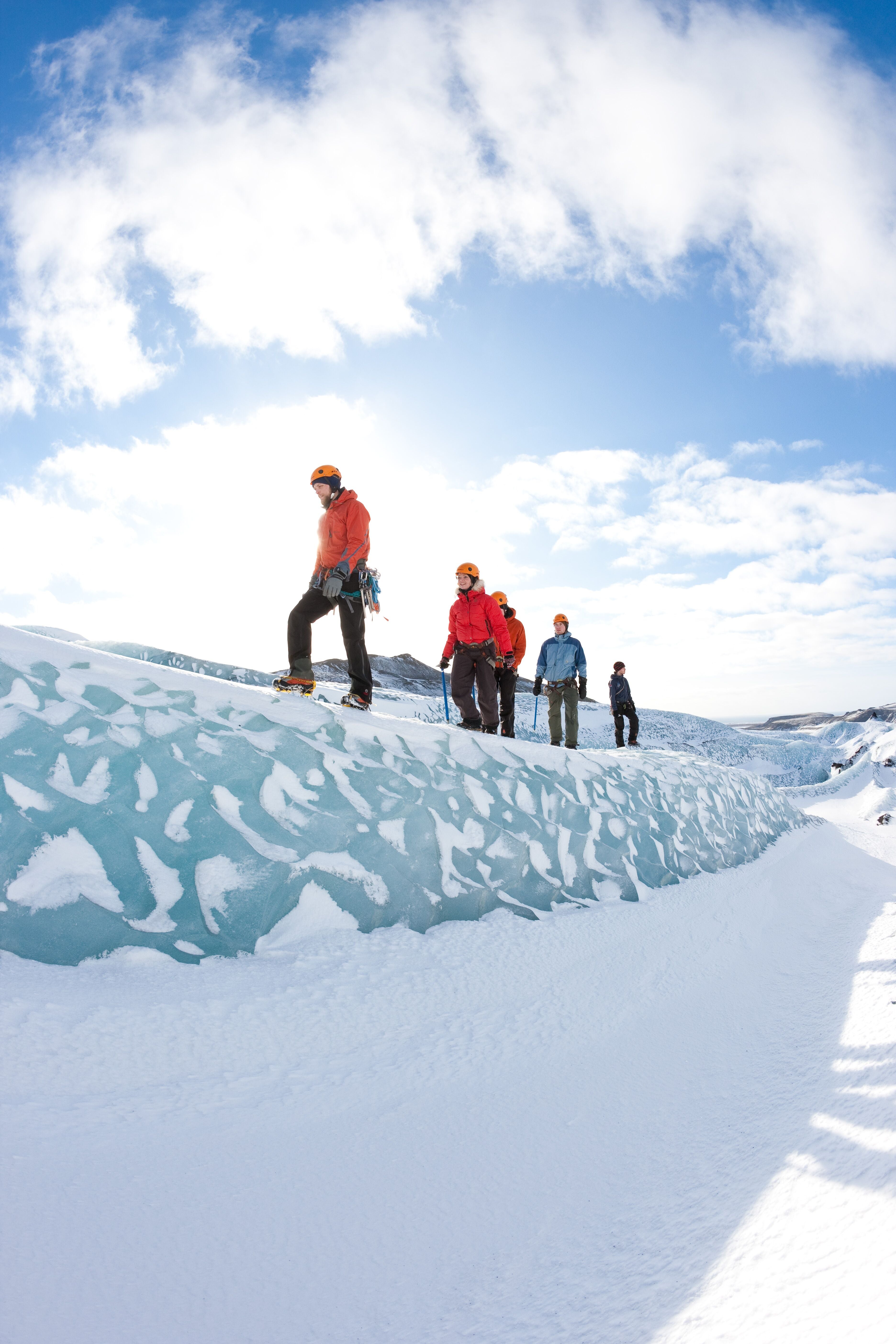 Group of people walking along a ridge of ice on Solheimajokull glacier.