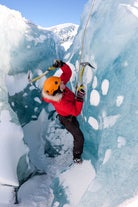 Person climbing Solheimajokull glacier using axes and crampons.