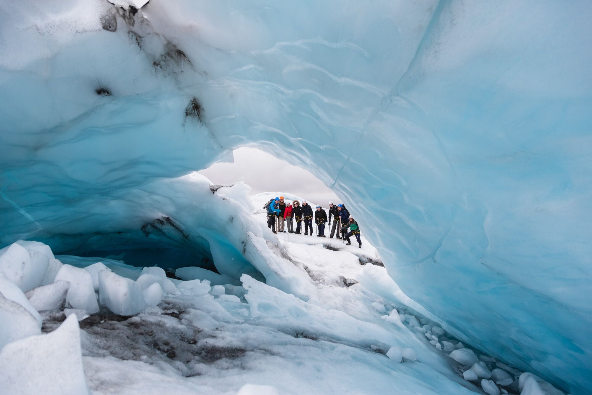 The group of glacier hikers peeking out of an ice tunnel