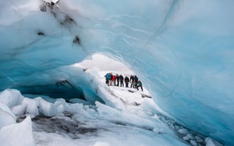 The group of glacier hikers peeking out of an ice tunnel