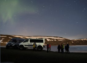 En gruppe mennesker står ved siden af en superjeep, mens mørket sænker sig