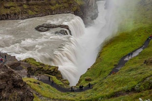 A birdseye view of people walking along the pathway next to the powerful Gullfoss falls on a 90 degree bend in the Hvita river.