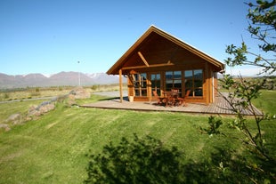 The exterior view of the wooden Family cottage in North Iceland with a table and chairs on the patio, countryside surroundings, 