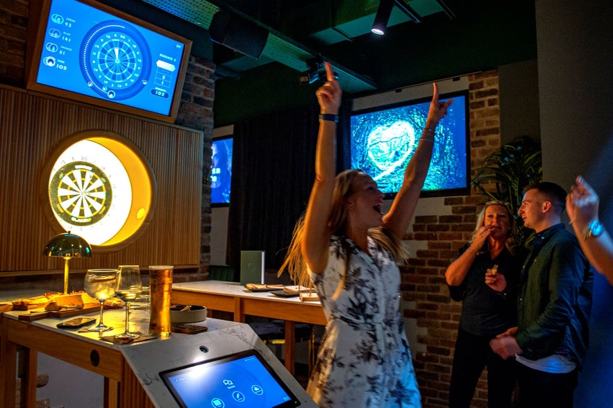 Guests playing interactive darts at Oche, a modern bar in Reykjavik.