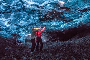 Dos personas en una cueva de hielo en Islandia, señalando algunas de las características únicas del hielo.