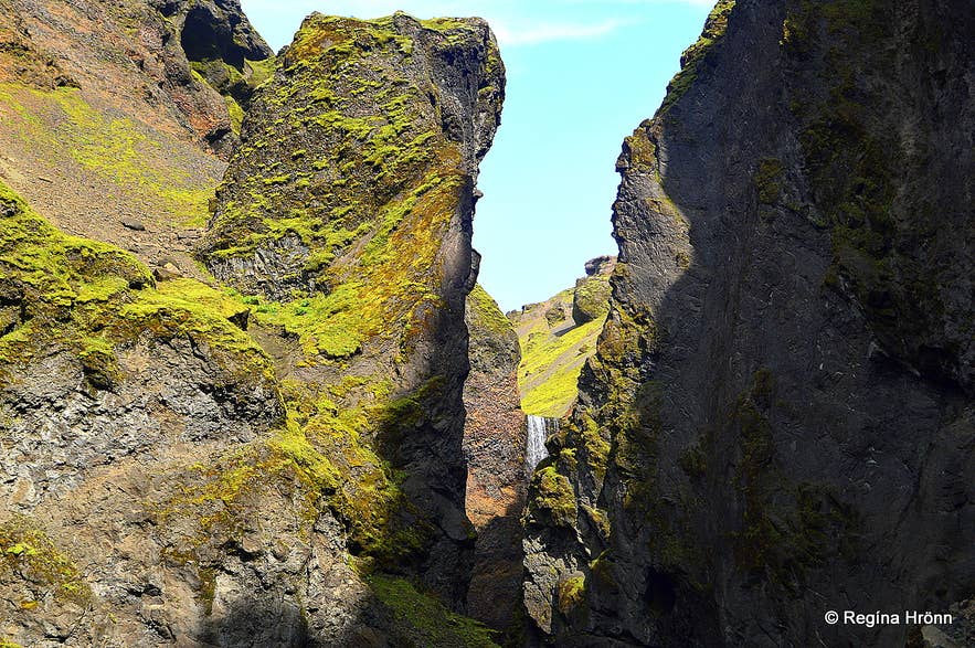 Moss-covered cliffs of Remundargil canyon with Remundargilsfoss waterfall in the distance
