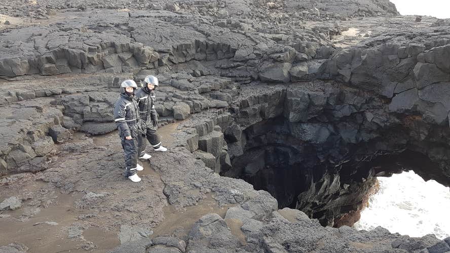 Two people in helmets and boiler suits standing on a ridge.