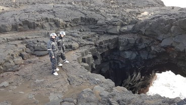 Two people in helmets and boiler suits standing on a ridge.