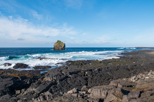 A lone rock cliff is seen standing near the shore of the Reykjanes peninsula.