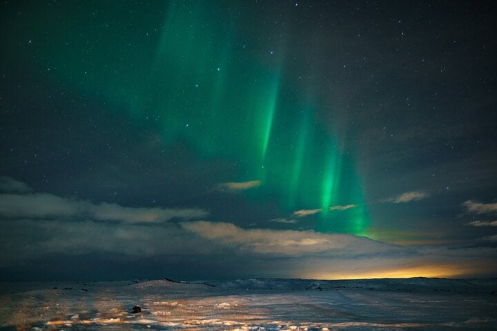 The northern lights lining up above the clouds and the starry night sky.