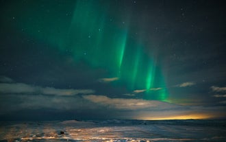 The northern lights lining up above the clouds and the starry night sky.