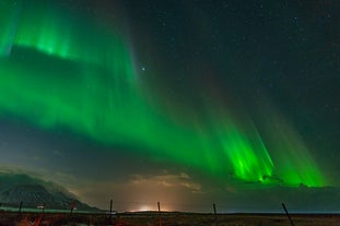 A curtain-like display of aurora illuminates a valley outside Reykjavik in Iceland.