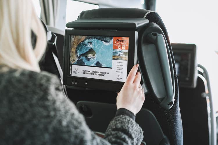 A touch screen inside a bus is being explored by a woman in the bus.