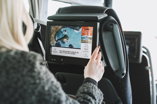A touch screen inside a bus is being explored by a woman in the bus.