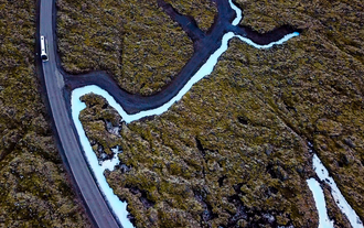 The lava fields in Iceland with a bus driving through them.
