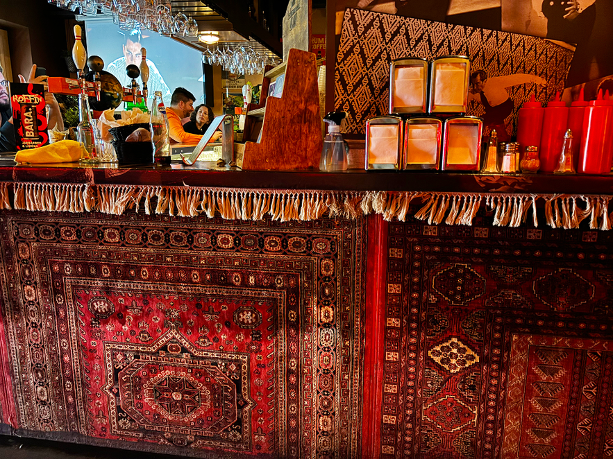 The bar at Lebowski Bar is wrapped in a Persian rug, of course