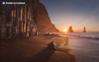 The sun setting in the background of the Reynisfjara Black Sand Beach on the South Coast of Iceland.